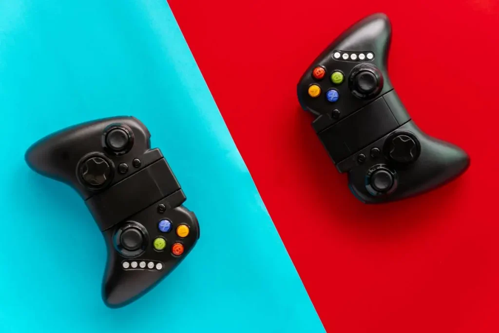 Dois joysticks pretos sobre fundo dividido em azul e vermelho, simbolizando a experiência imersiva nos jogos.