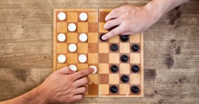 Duas pessoas jogando damas. Mãos movendo peças no tabuleiro.
