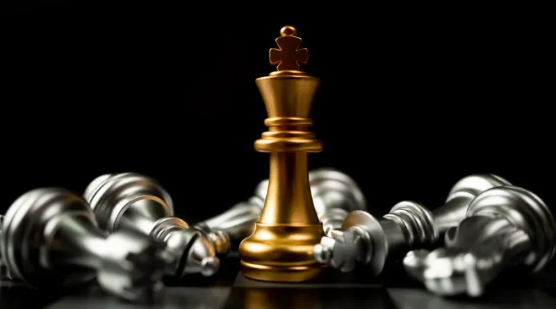 Rei dourado em destaque entre peças caídas. Símbolo de vitória e estratégia.