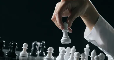 Mão movendo peça de xadrez branca. Foco em estratégia e tomada de decisões.