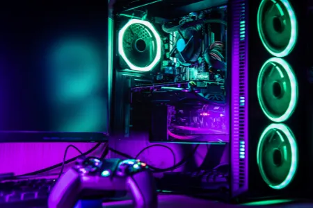 PC gamer ligado com luzes RGB verdes e roxas, gabinete transparente, controle de videogame no primeiro plano