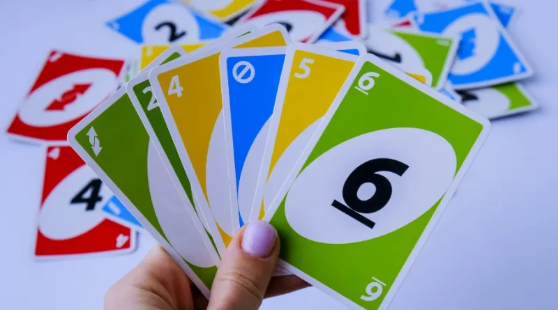 Mão segurando cartas de Uno coloridas.