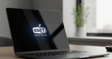 Laptop exibindo o logotipo "ESET Internet Security" na tela preta, sobre uma mesa de madeira em um ambiente de escritório.