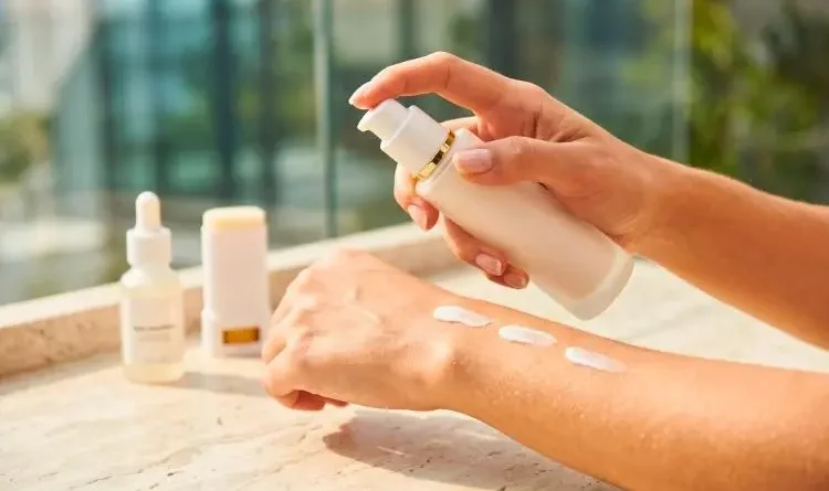 Close de mãos femininas aplicando protetor solar