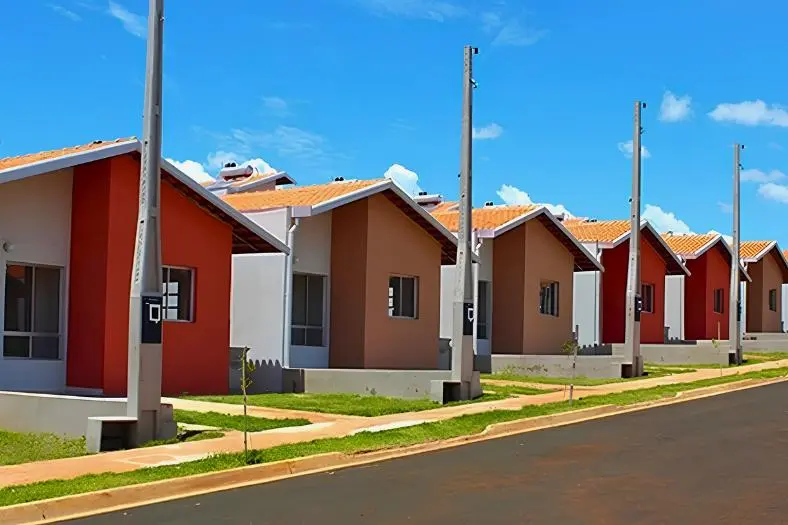 Fileira de casas populares padronizadas e coloridas em um conjunto habitacional do programa Minha Casa Minha Vida.